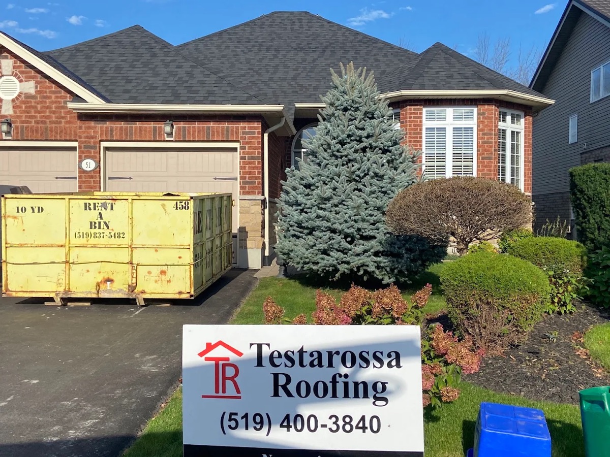 Finished brick bungalow with a new dark grey shingle roof, bin still staged in the driveway