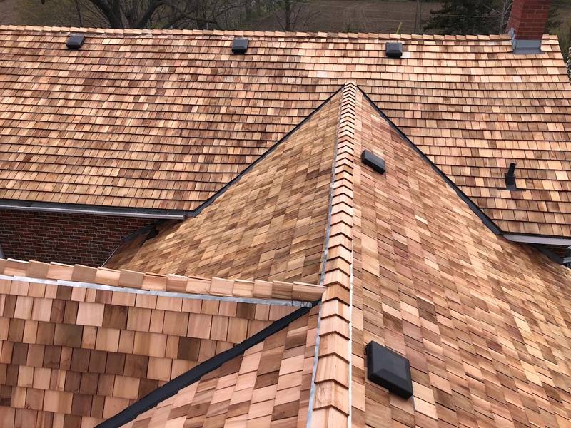 Completed cedar shake roof seen from above, hips and ridges capped and vents flashed in