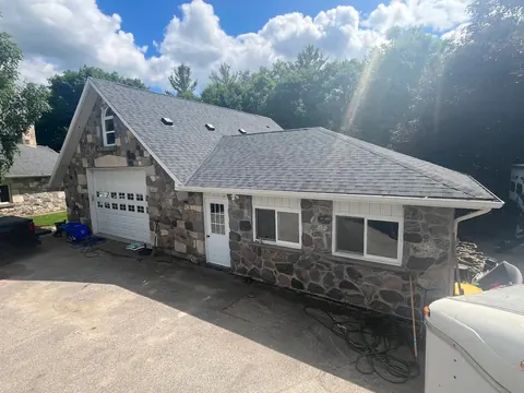 Stone garage and addition with a new charcoal shingle roof, fresh eavestrough and vents