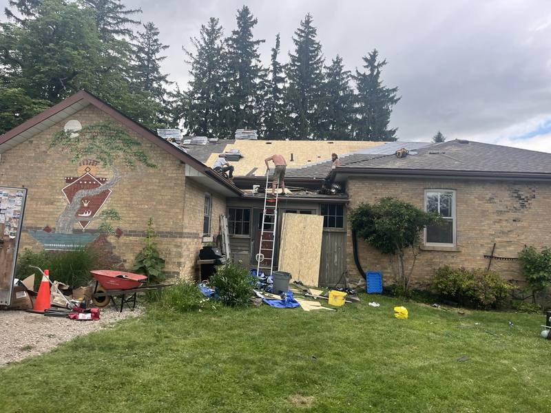 Testarossa Roofing crew re-roofing a bungalow, ladder up and new roof sheathing going down