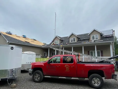 Red Testarossa Roofing pickup truck with logo decal, parked in front of a home mid re-roof